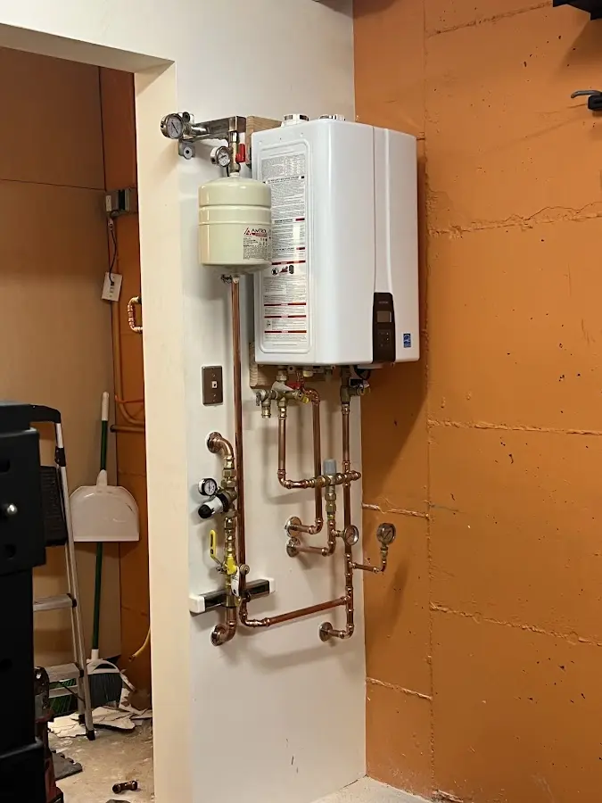 Plumbing technician inspecting water heater connections in North Collins